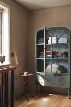 an old china cabinet in the corner of a room next to a table with towels on it