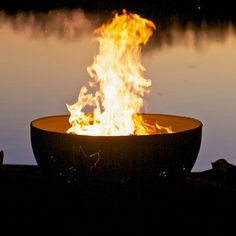 a fire pit sitting on top of a lake filled with lots of water and flames