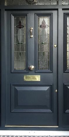 a black front door with two sidelights and stained glass panels on the top half