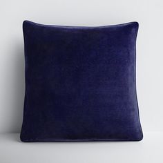 a blue velvet pillow on a white surface