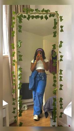 a woman taking a selfie in front of a mirror with ivy growing on it