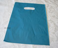 a blue shopping bag sitting on top of a white table cloth covered bed sheet with lace