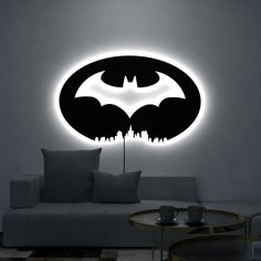 a living room with a couch, table and batman symbol on the wall above it