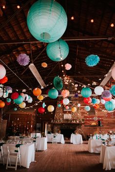 a room filled with lots of tables covered in paper lanterns