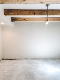 an empty room with white walls and wood beams on the ceiling is pictured in this image