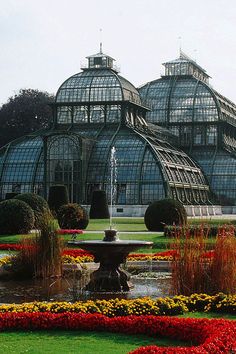 a large glass house with many flowers around it