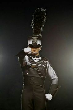 a man dressed in black and white with a feathered hat on top of his head