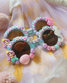 Be Summer and Beach Ready with our Custom BLING  Mermaid #Scarlettsunnies ️️️️ How awesome are these‼️ I mean, They are just so E-X-T-R-A ‼️ ️️️ Pink Shell Sunnies 3 -10 yo Blue Flower Sunnies 1 -8 yo DM to request for  ️ Name Letter Beads Color Rainbow Rose gold Pink with Black Letters otherwise, it will be sent with Rainbow letters. ️Your Sunnies will be bedazzled with  Jelly colored Rhinestones Imitation Ivory Pearls Mermaid Pearls How about Pair your Sunnies with Matching Hairclips and Bracelets 🧡 Check my other stuff Stocks limited  🛒 DM to order Please note that Designs may vary. Each #ScarlettSunnies pair is unique. 🚫 WARNING! CHOKING HAZARD! Contains small parts. Please do not leave children unattended while wearing. As these are hand made by me, it wouldn't be 100% perfect, but Sunglasses Decorated, Handmade Sunglasses For Summer Beach, Whimsical Sunglasses With Uv Protection For Beach, Seashell Sunglasses, Whimsical Beach Sunglasses With Uv Protection, Summer Stuff, Sunglasses With Beads On Them, Cute Personalized Summer Sunglasses, Mermaid Sunglasses