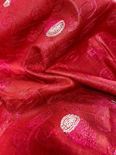 red fabric with white and pink designs on the side, in close up view from above