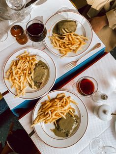 two white plates topped with french fries and gravy on top of a table