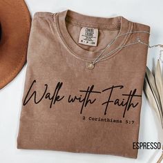 ABOUT OUR: Bible Verse Tshirt Express your faith with our "Walk with Faith" t-shirt, featuring the powerful 2 Corinthians 5:3 verse. Perfect for any Christian person looking to wear a faith-based shirt that speaks to their spiritual journey. This Christian shirt offers a minimal Christian quote design for those who prefer subtle yet impactful expressions of belief. Ideal as a religious shirt for daily wear, Bible studies, or gifts, this Christian quote tee serves as a reminder to walk with confi Christian Tshirt Design Ideas Minimalist, Christian Tshirt Design Ideas, Christian Attire, Christian Shirts For Women, Christian Tshirt Design, Faith Clothing, Bible Verse Shirt, Stencil Material, Christian Quote