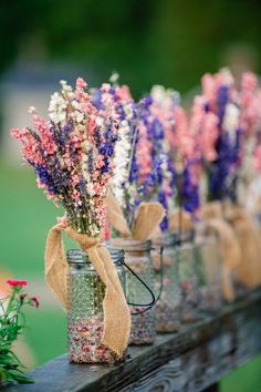 mason jar filled with flowers sitting on top of a wooden table next to other jars