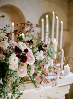 flowers and candles are arranged on a mantle