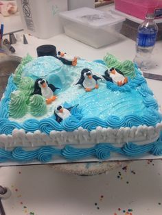 a birthday cake decorated with penguins and seaweed