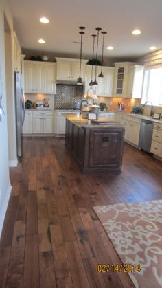 a large kitchen with wooden floors and white cabinets