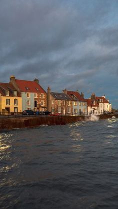 some houses by the water under a cloudy sky