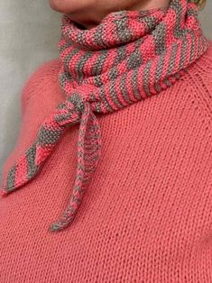 a woman wearing a pink sweater with a gray and white striped scarf around her neck