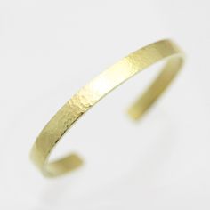 A captivating and stunning piece, this 14k yellow gold cuff bracelet has an eye-catching hand hammered finish adding depth and visual appeal.  The cuff measures 6mm wide and 2mm thick making it a substantial accessory for your wrist!  Crafted from high-quality 14ky gold, this cuff bracelet showcases the warmth and richness of this popular precious metal, built to stand the test of time. The cuff pictured is not the exact one that you will receive, but it will be the same design. There may be sli Elegant Hand Forged Yellow Gold Bangle, Modern Hammered Yellow Gold Bracelets, Modern Hammered Yellow Gold Bangle, Hammered Yellow Gold Bangle For Anniversary, Classic Hammered Yellow Gold Bracelets, Formal Hammered Yellow Gold Cuff Bracelet, Formal Yellow Gold Hammered Cuff Bracelet, Formal Yellow Gold Hammered Bangle, Modern Hammered Bangle For Formal Occasions