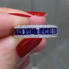 a woman's hand holding a diamond and sapphire ring