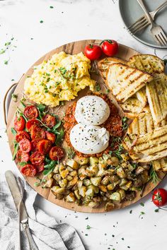 a wooden plate topped with eggs, toast and veggies on top of a white table