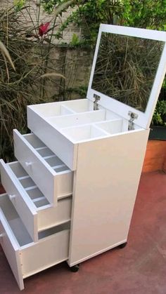 a white vanity with drawers and a mirror on the top shelf in front of some bushes