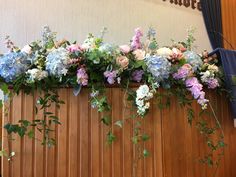 an arrangement of blue and pink flowers in a window box with greenery on the side