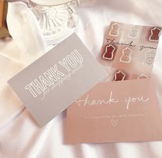 two thank you cards sitting on top of a bed