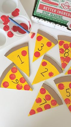 paper cut out to look like pizza slices with numbers on them and paintbrushes