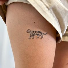 a woman's thigh with a tattoo of a tiger on it and the word tiger written in black ink