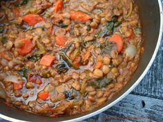 a pot filled with beans and carrots on top of a wooden table