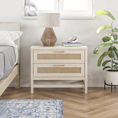 a bedroom with a bed, nightstand and plant on the side table next to it