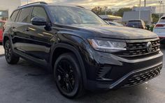 the front end of a black volkswagen suv parked in a parking lot with other cars