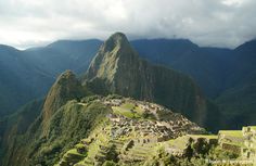 the ruins of machaca picach are surrounded by green mountains and dark clouds in the distance