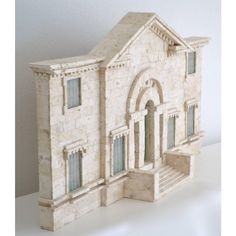 a small model of a house with stairs and windows on top of a white table