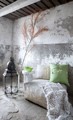 a white couch sitting next to a green vase on top of a table