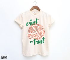 Satisfy your style cravings with this vintage-inspired Pizza tee! Featuring a hand-drawn pizza graphic this shirt adds a slice of retro fun to any casual look. The text reads, "In Crust We Trust."  We use professional quality DGT printing on all our apparel. Direct-to-garment, or DTG, is a high quality printing method that sprays ink directly onto the garment so there is no peeling or cracking. This fabulous graphic will be printed on a Comfort Colors Unisex T-Shirt. Please refer to the size cha In Crust We Trust, Food Graphic Tee, Pizza Tshirt Design, Pizza T Shirt, Pizza Graphic, Pizza Tee, Pizza Tshirt, Pizza Shirt, Graphic Tee Vintage