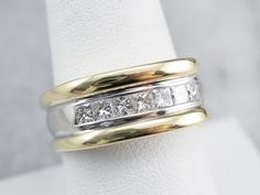 This diamond band makes a bold statement and could be worn by either a man or a woman! Weighty and sleek, this ring is crafted from two tones of 18 karat gold and looks impressive on the hand. The diamonds display as a seamless row of fiery sparkle, enhancing the luxuriousness of this well-designed band. Metal: 18K Yellow and White Gold Gem: 7 Diamonds totaling .52 Carats, VS in Clarity, H in Color Width of Band: 9 mm Height off Finger: 4.2 mm Ring Size: 8.75 Marks: "18K GS" Stamped on the insid Luxury Polished Finish Women's Bands, Band Metal, Chunky Ring, Stacking Bands, Cameo Ring, Chunky Rings, Ring Stacking, Diamond Wedding Ring, Unisex Ring