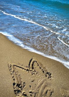 the word love is written in the sand on the beach next to the ocean and waves