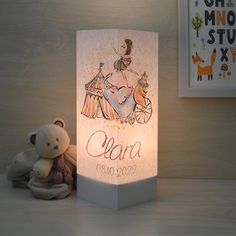 a small teddy bear sitting next to a lit up card with the name ciara on it