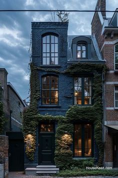 an old brick building with ivy growing on it's side and windows above the door