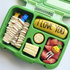 a green lunch box filled with fruit and veggies on top of a white table