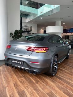 the back end of a silver mercedes car in a showroom with wood flooring