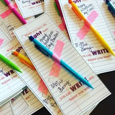 several pens are lined up on top of notebooks that have writing paper attached to them