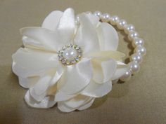 a close up of a white flower on a beaded bracelet with pearls and crystals