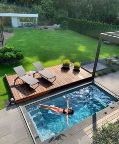 a woman swimming in a small pool surrounded by greenery and wooden decking area