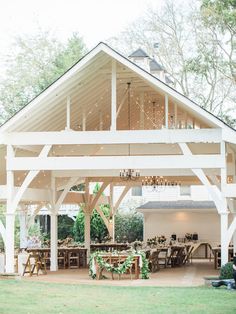 an outdoor dining area with tables and chairs under a white roof covered in string lights