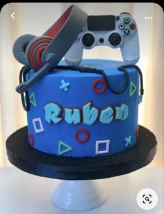 a blue cake with video game controllers on top and the word ruben spelled out