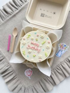 a birthday cake sitting on top of a table next to a container and spoons