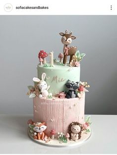 a three tiered cake with animals and flowers on the top is decorated in pastel colors