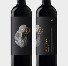 two bottles of red wine with a rock on the top and one bottle in front